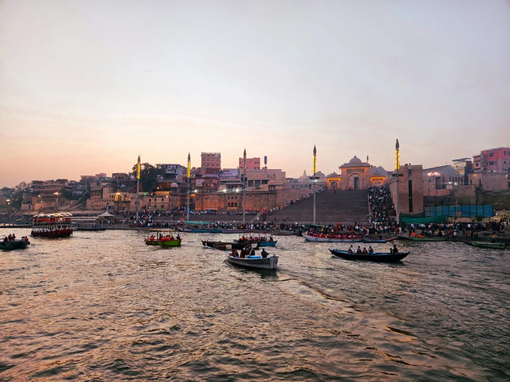 Boats on the Ganges River with Varanasi Ghats at sunset, showcasing Indian cultural heritage.