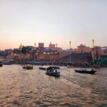 Boats on the Ganges River with Varanasi Ghats at sunset, showcasing Indian cultural heritage.